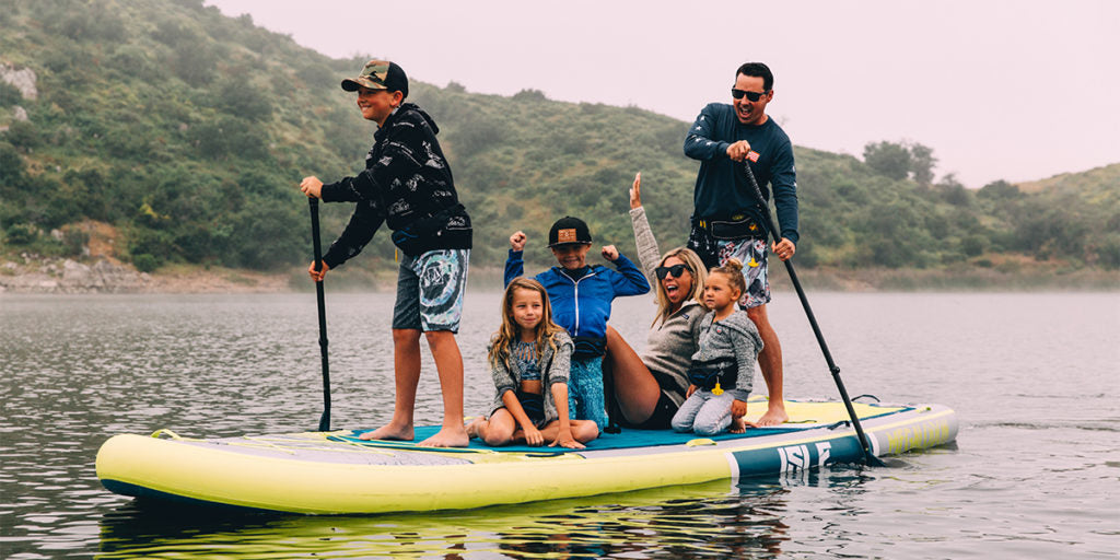 Family with kids paddle boarding together