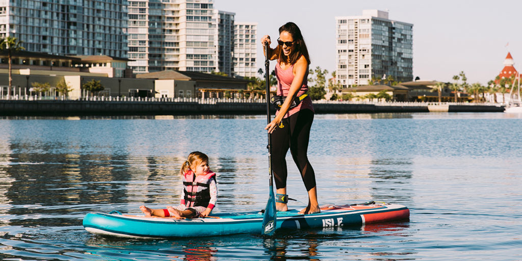 Mom paddle boarding with her daughter on board