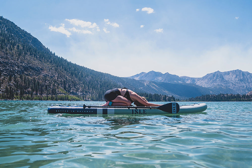 woman doing child's pose on paddle board