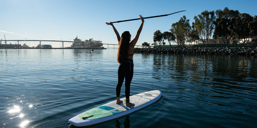 woman holding SUP paddle above her head