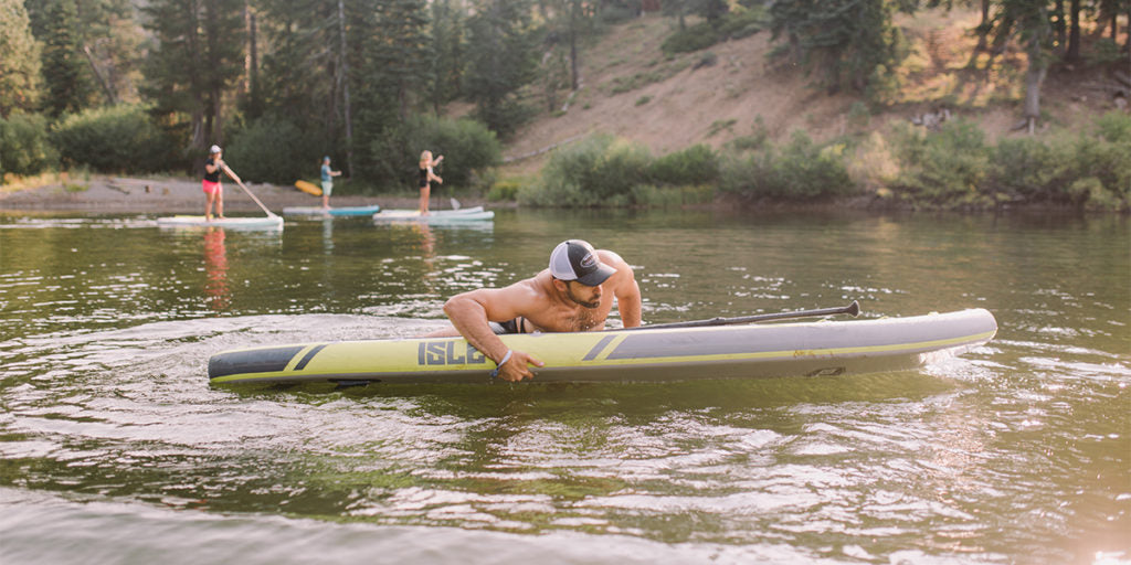 man getting back on his paddle board after a fall